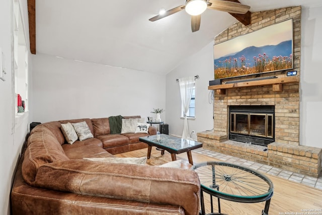 living room with lofted ceiling with beams, a fireplace, wood finished floors, and a ceiling fan