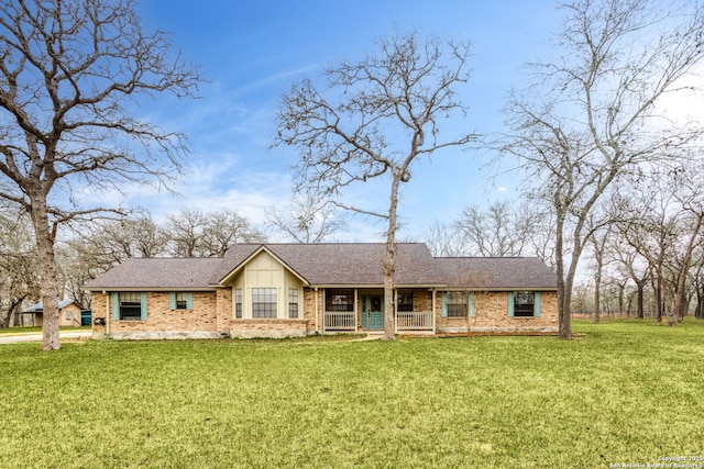 view of front of house featuring brick siding, a shingled roof, and a front yard