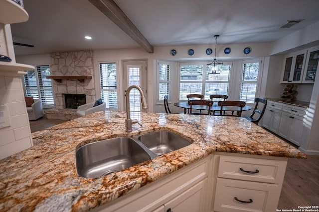 kitchen featuring visible vents, dark wood finished floors, light stone countertops, white cabinetry, and a sink