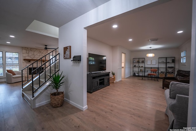 living room featuring recessed lighting, visible vents, wood finished floors, baseboards, and stairs