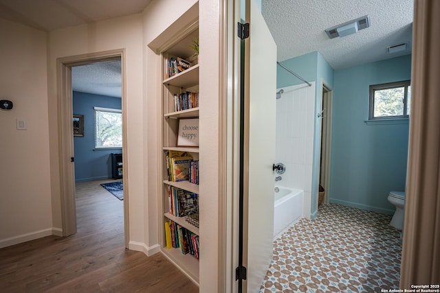 bathroom with a textured ceiling, visible vents, plenty of natural light, and toilet