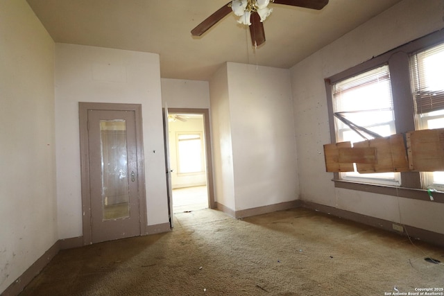 spare room featuring light carpet, ceiling fan, and baseboards