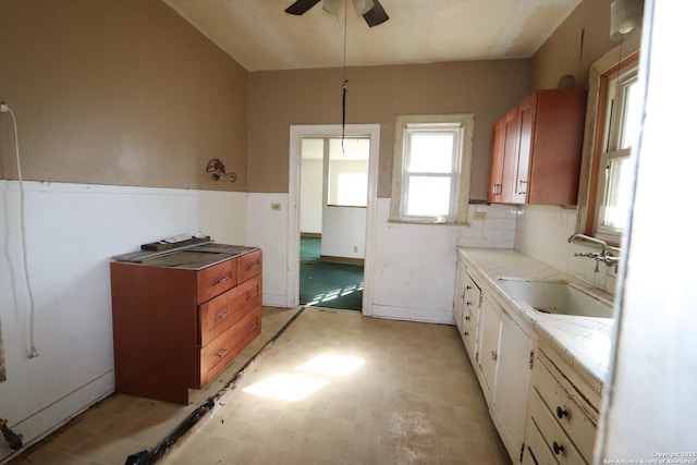 kitchen with brown cabinets, a sink, light floors, and ceiling fan