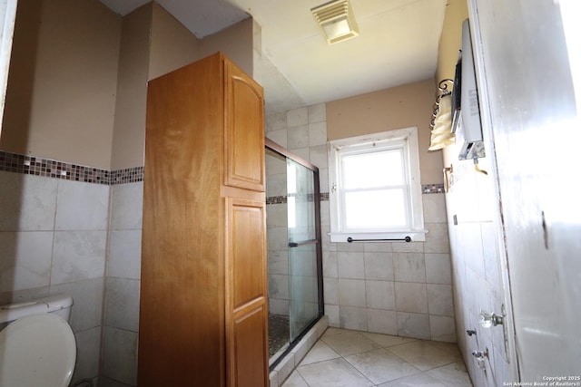 full bathroom with visible vents, tile walls, a shower stall, and tile patterned floors