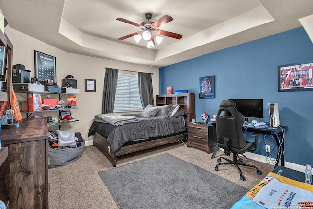 bedroom with a ceiling fan, baseboards, a raised ceiling, and carpet flooring