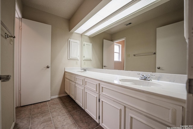 bathroom featuring tile patterned floors, visible vents, a sink, and double vanity