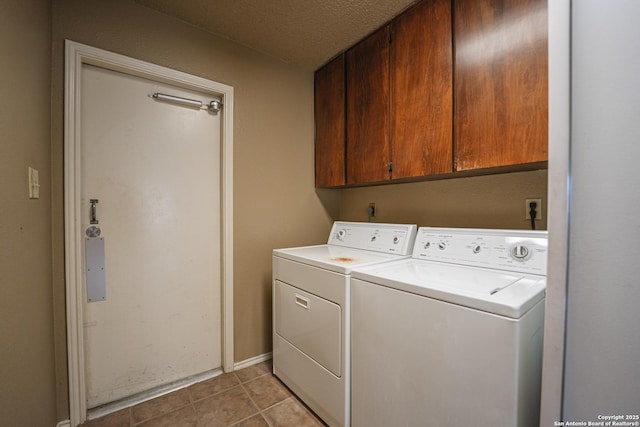 washroom with cabinet space, washer and clothes dryer, a textured ceiling, and light tile patterned flooring