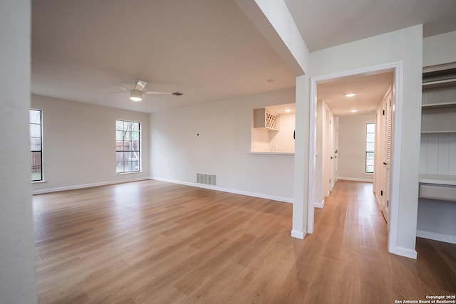 spare room with light wood finished floors, baseboards, visible vents, and a ceiling fan