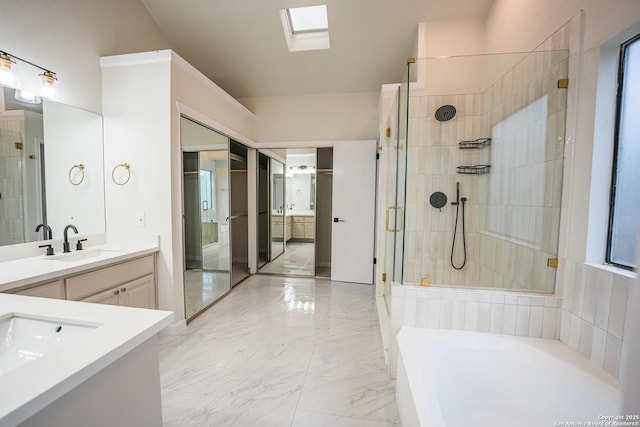 full bathroom with a skylight, marble finish floor, vanity, a shower stall, and a bath