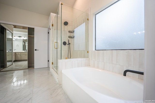 bathroom featuring a stall shower, marble finish floor, a garden tub, and vanity