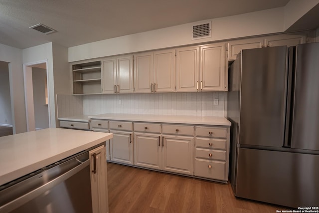 kitchen featuring stainless steel appliances, light countertops, light wood-style flooring, and visible vents