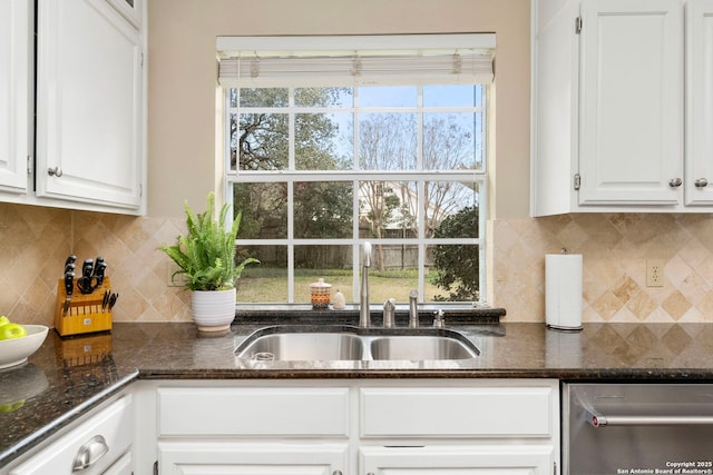 kitchen featuring dark stone counters, tasteful backsplash, a sink, and white cabinetry