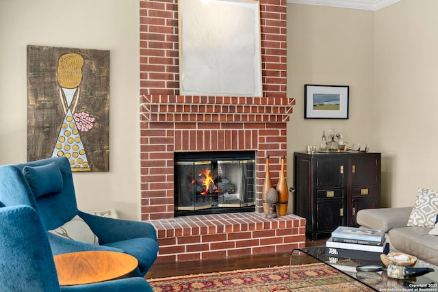 living room featuring a brick fireplace, crown molding, and wood finished floors