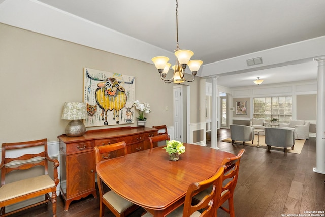 dining space featuring visible vents, dark wood finished floors, ornate columns, a chandelier, and a decorative wall