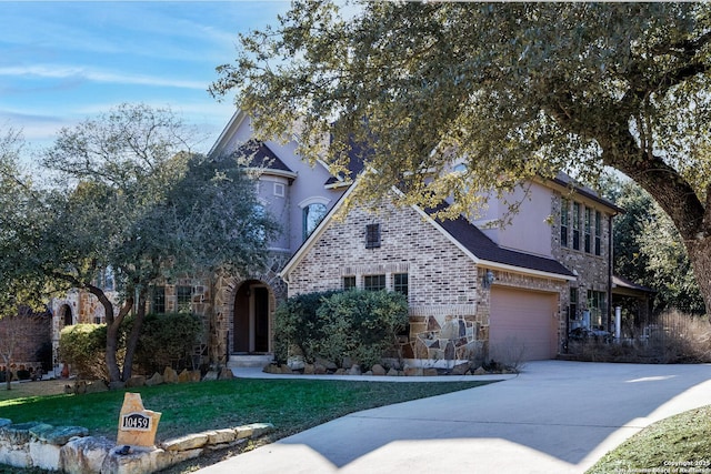 view of front of home with driveway, stone siding, a front lawn, and an attached garage