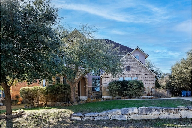 obstructed view of property featuring stone siding and a front lawn