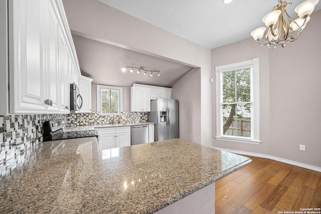 kitchen with stainless steel appliances, backsplash, stone countertops, white cabinets, and a peninsula