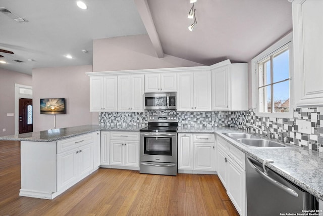 kitchen featuring lofted ceiling with beams, stainless steel appliances, a peninsula, a sink, and white cabinets