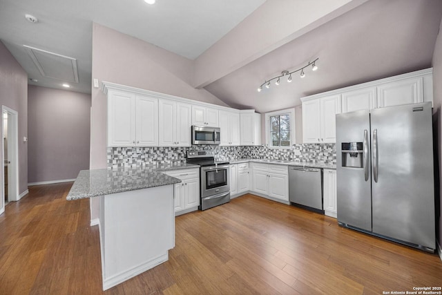 kitchen with a peninsula, light stone countertops, white cabinetry, and stainless steel appliances