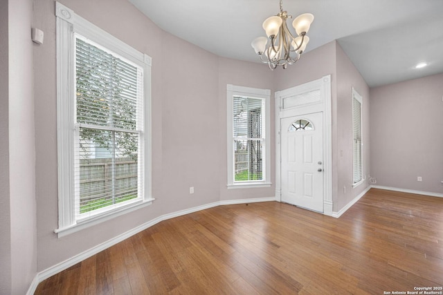 foyer with baseboards, wood finished floors, and an inviting chandelier