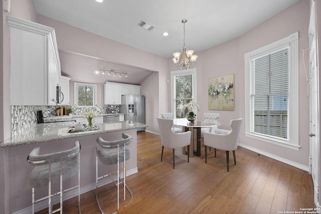 dining space with a chandelier, dark wood-style flooring, visible vents, and baseboards