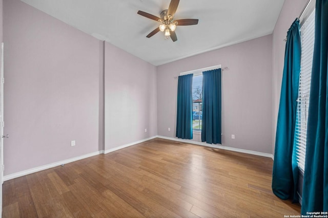 spare room featuring light wood finished floors, baseboards, and a ceiling fan