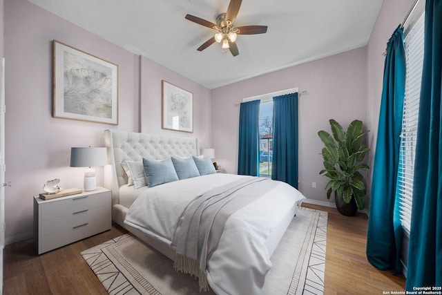 bedroom featuring ceiling fan, baseboards, and wood finished floors