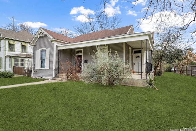 view of front facade with a front lawn, roof with shingles, and a porch