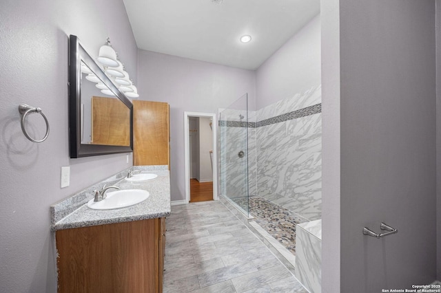 bathroom featuring a stall shower, a sink, and double vanity