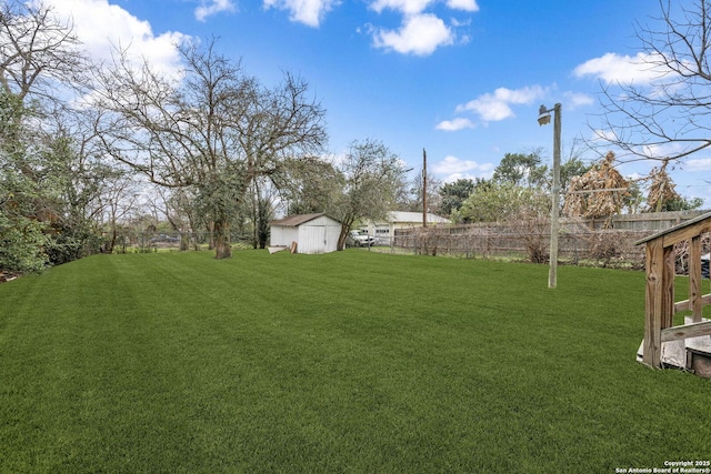 view of yard featuring a shed, fence, and an outdoor structure