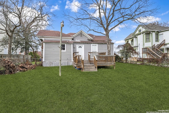 rear view of house with a yard, fence, and a wooden deck