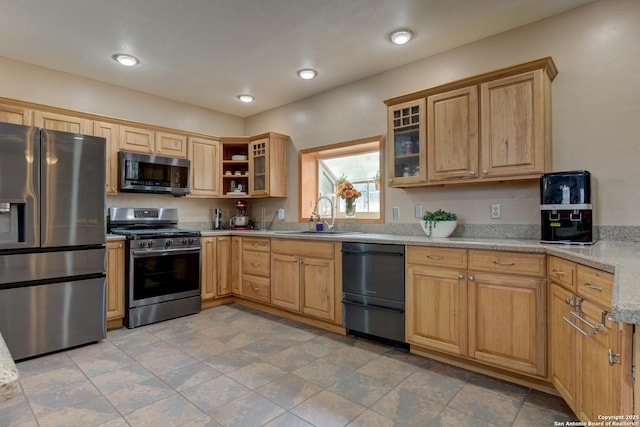 kitchen with stainless steel appliances, recessed lighting, glass insert cabinets, a sink, and light stone countertops