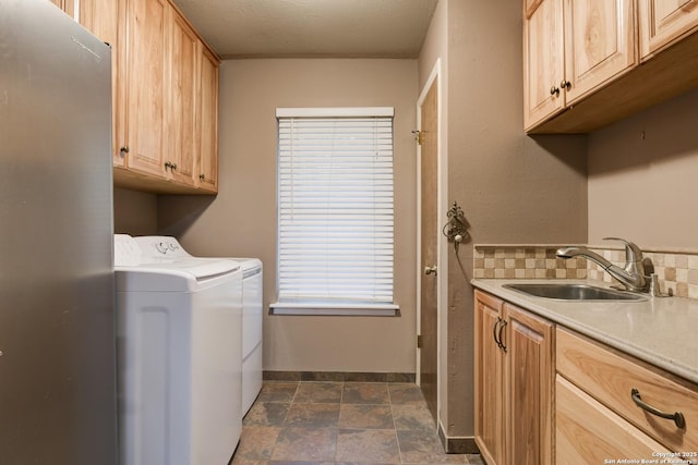 laundry room featuring a sink, baseboards, independent washer and dryer, cabinet space, and stone finish floor