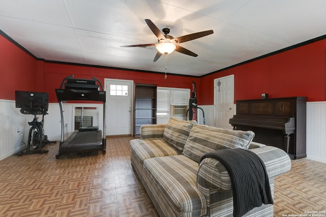 living room featuring a ceiling fan, cooling unit, a wainscoted wall, and crown molding