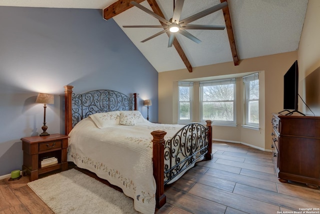 bedroom featuring lofted ceiling with beams, wood finished floors, a ceiling fan, and baseboards