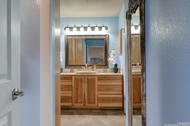 bathroom featuring a textured wall, stone finish floor, and vanity