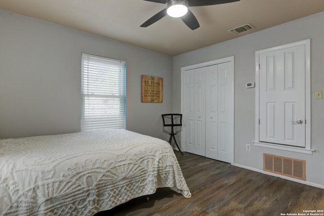 bedroom with a closet, visible vents, dark wood finished floors, and ceiling fan