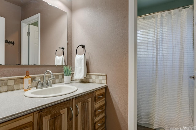 full bathroom featuring a textured wall and vanity