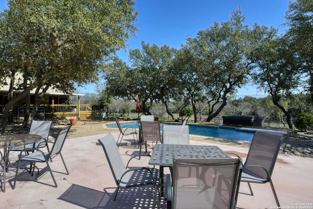 view of patio featuring outdoor dining area, fence, and an outdoor pool