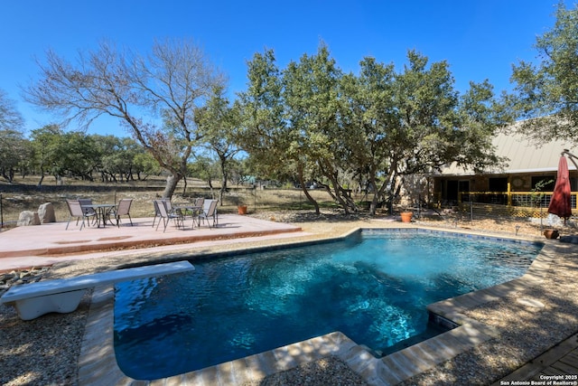 pool featuring fence, a diving board, and a patio