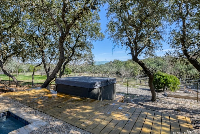 deck with a hot tub and fence