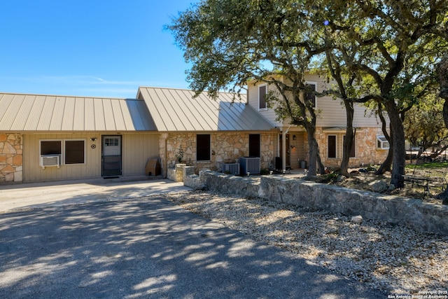 multi unit property with stone siding, cooling unit, a standing seam roof, and metal roof