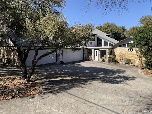 mid-century inspired home with a garage, concrete driveway, and fence