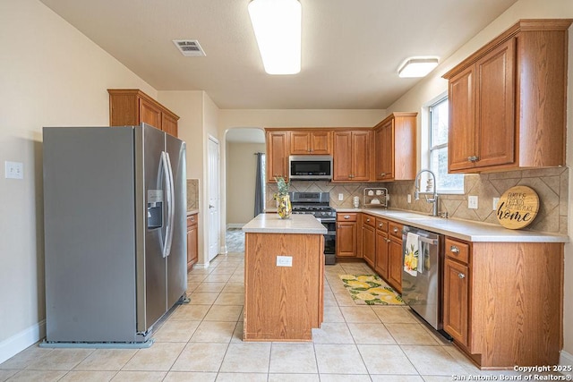 kitchen featuring stainless steel appliances, light countertops, visible vents, a kitchen island, and a sink