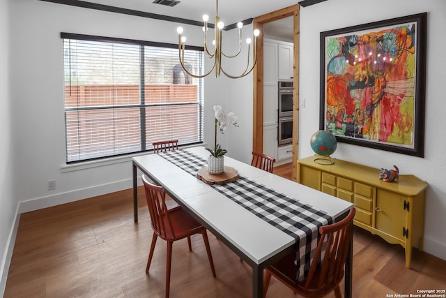 dining area with an inviting chandelier, baseboards, visible vents, and wood finished floors