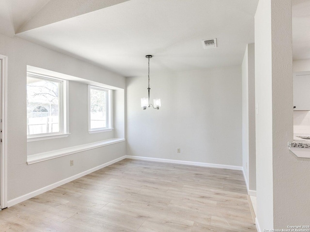 unfurnished dining area with light wood-type flooring, an inviting chandelier, baseboards, and visible vents