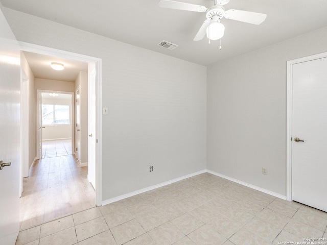 empty room featuring ceiling fan, light tile patterned floors, visible vents, and baseboards