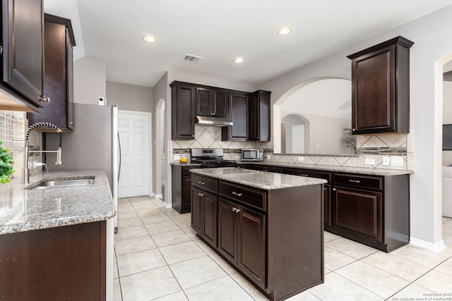 kitchen featuring dark brown cabinetry, under cabinet range hood, visible vents, and light tile patterned floors