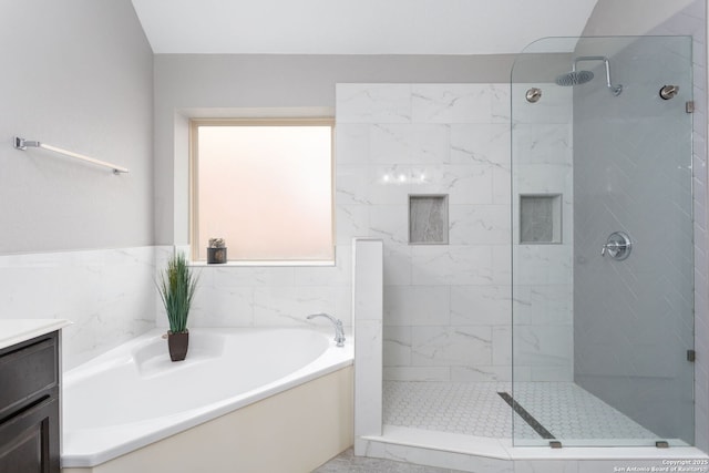 bathroom featuring a tile shower, a bath, and vanity