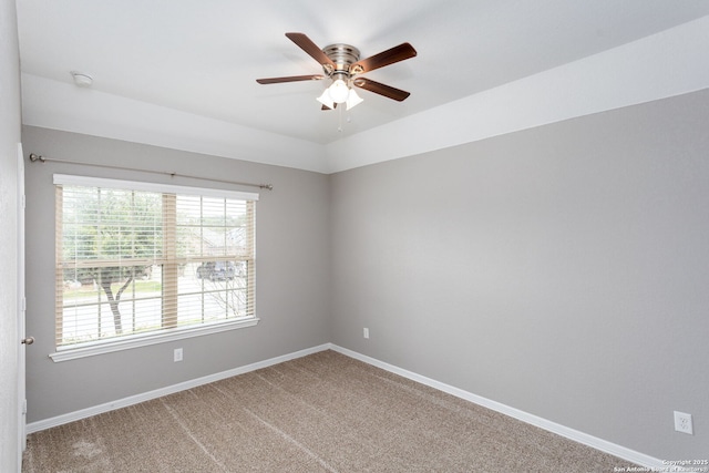 carpeted empty room with a ceiling fan and baseboards